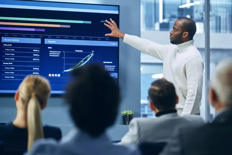 A sales coaching presentation where a man is reporting on sales metrics